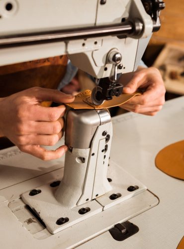 close-up-shoemaker-using-sewing-machine_171337-12308