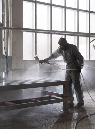 man-spraying-powder-paint-from-gun-full-shot_23-2149878780