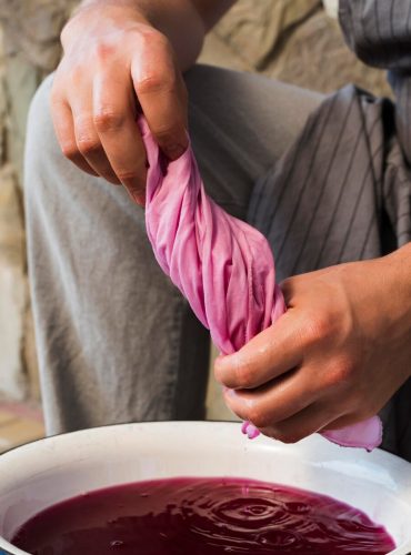 man-squeezing-cloth-from-pink-natural-pigment_23-2148734405
